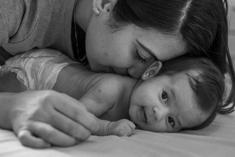 mãe beijando as costas da filha