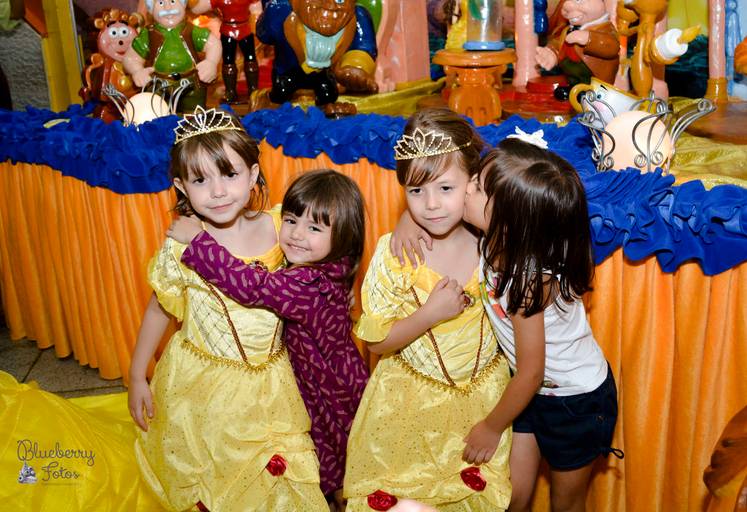 gêmeas fantasiadas de princesa sendo abraçadas por outras crianças