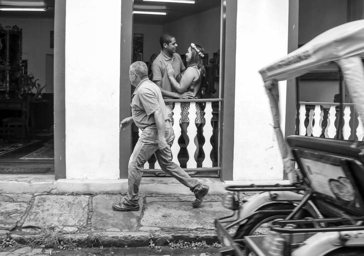 noivos érica e Helton se abraçando durante pré-wedding, pessoas e carros passando na rua em ouro preto minas gerais