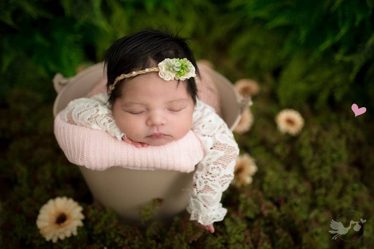 Foto newborn jardim secreto com flores usando roupinha de renda branca e head band de folha