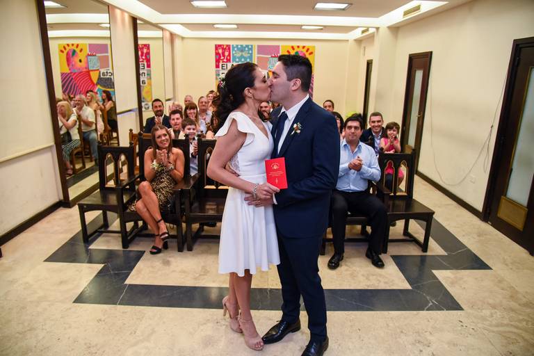 Boda en el civil de Uruguay, CABA. El beso de los novios con todos sus invitados detrás. Marcos Pasquare fotógrafo de bodas