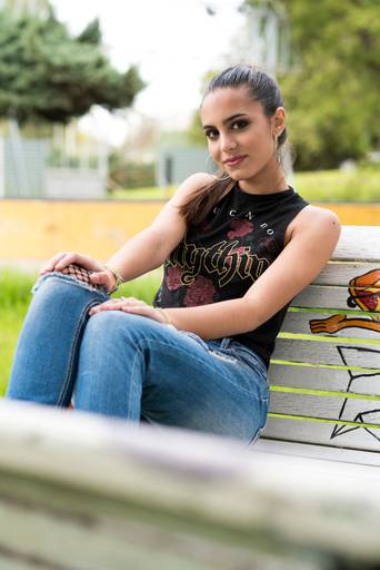 Carla en el book de exteriores sentada en un banco de plaza con motivos de comic. Marcos Pasquare fotógrafo de quince años.