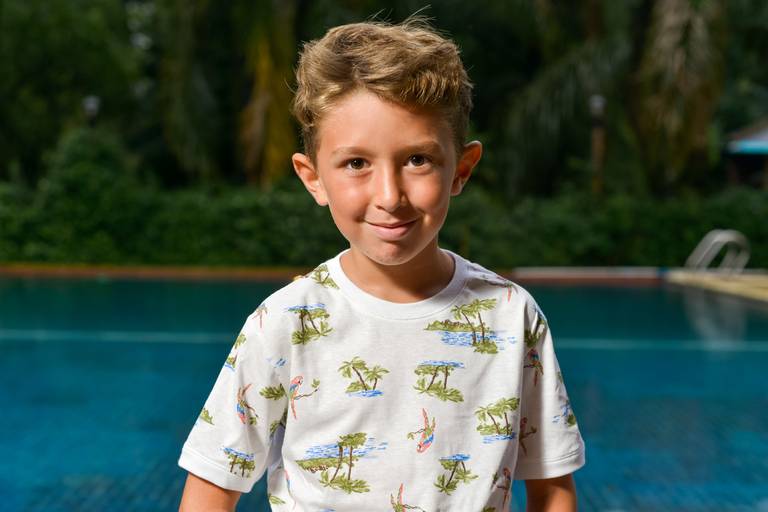 Niño rubio. Retrato infantil en exterior día de lluvia con una piscina de fondo. Marcos Pasquare fotografía de eventos.