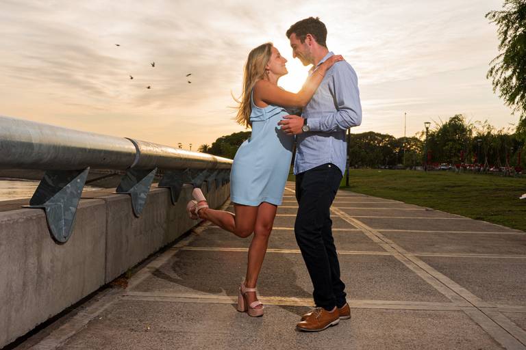 La novia levante el pie, las aves vuelan detrás de ellos y el sol pasa a contraluz. Costanera norte, CABA. Sesión pre boda. Marcos Pasquare Fotógrafo de Bodas.