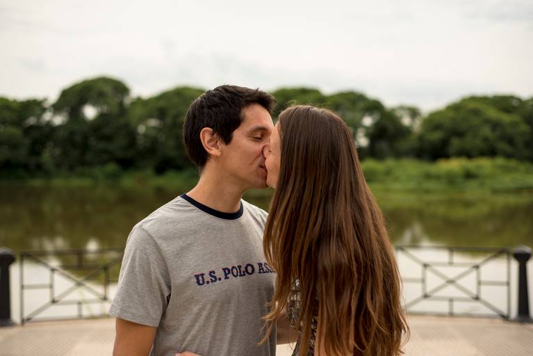 Sesión pre boda en la Costanera Sur, CABA. Los novios se besan suavemente con los copiosos arboles de fondo. Reserva ecológica. Marcos Pasquare Fotógrafo de Bodas.