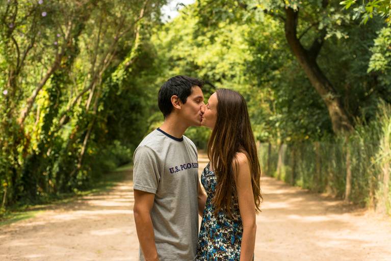 Sesión pre boda en la Costanera Sur, CABA. Los novios se besan en el camino dentro de un techo de arboleda. Reserva ecológica. Marcos Pasquare Fotógrafo de Bodas.