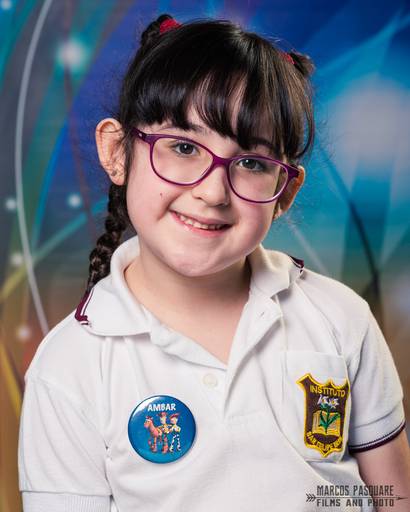 Niña con anteojos posa con una hermosa sonrisa para su retrato escolar 2020. Tiene trenzas y el pelo negro. Marcos Pasquare Fotografía escolar. San Felipe Neri. Mataderos. Chicago. Nueva Chicago,