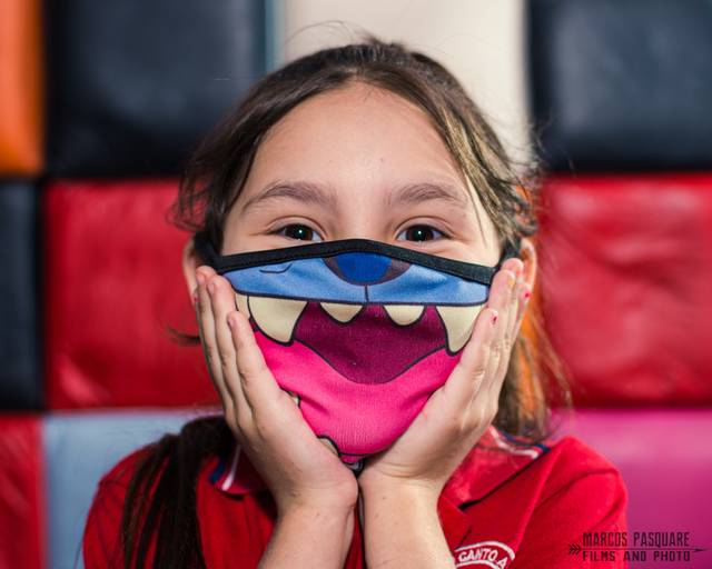 Fotografía de alumna de primer grado con barbijo. Ella sonríe a pesar de tener tapada la boca. Lilo y stich. Retrato escolar. Fotografía infantil. Instituto Canto a la vida.
