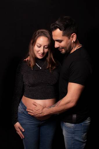 embarazada y su pareja fondo negro ropa casual, en interior