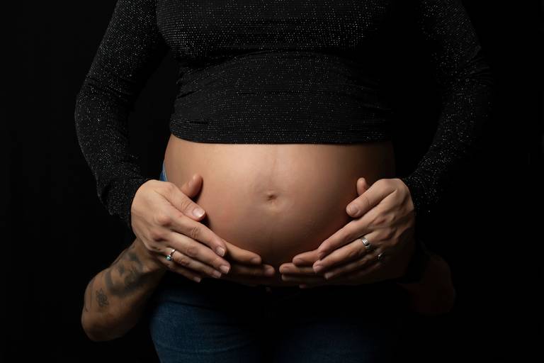 embarazada y su pareja fondo negro ropa casua, en interiorl