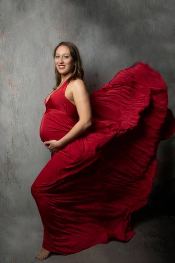 embarazada con vestido rojo , tela flotando, en interior