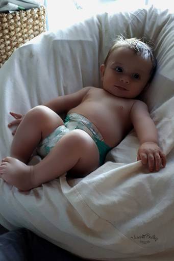 bebe en pañales sobre puf blanco