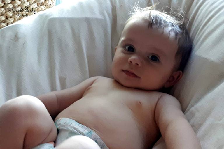 bebe en pañales sobre puf blanco