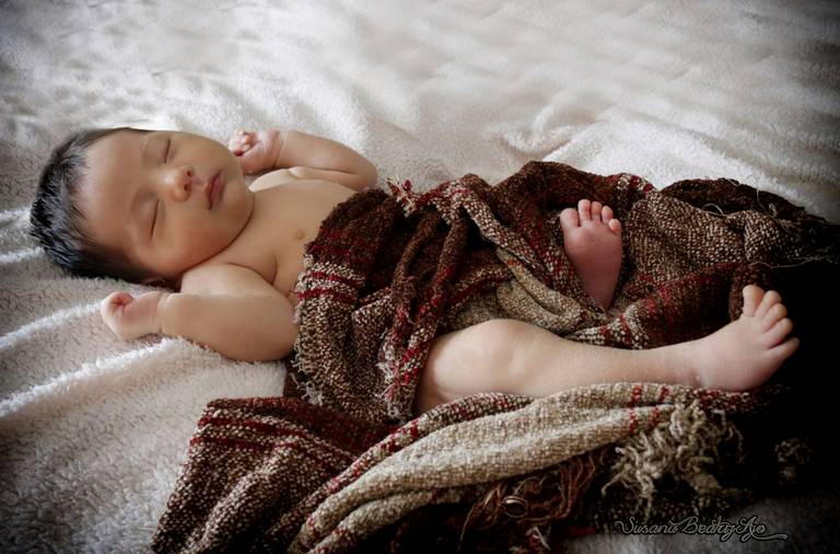 newborn - bebe sobre fondo blanco con tejido textil marron