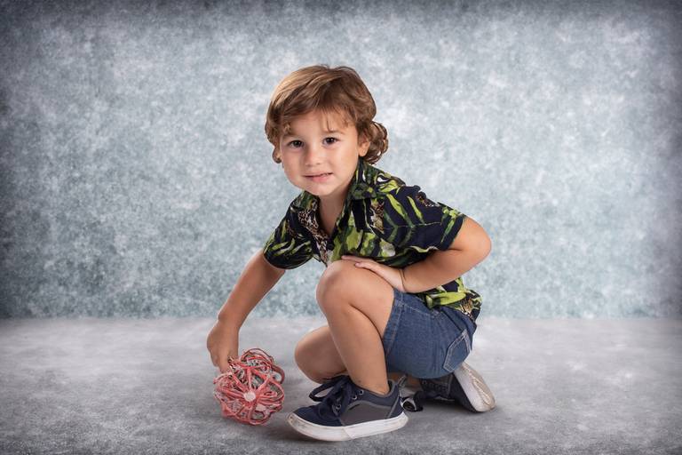 niño agachado con juguete