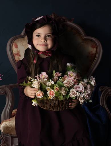 Retrato de niña con vestuario vintage con un cesto con flores sentada en un sillón antiguo fine art