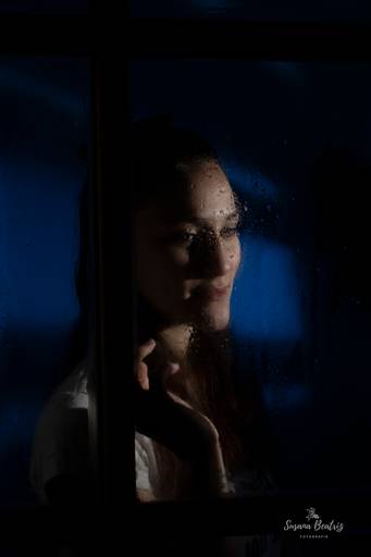 retrato chica mirando a través de una ventana un dia de lluvia