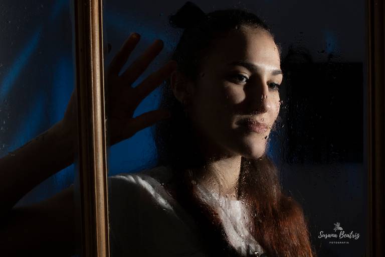 retrato chica mirando a través de una ventana un dia de lluvia