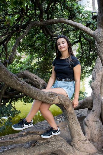 quinceañera sentada en un tronco de árbol