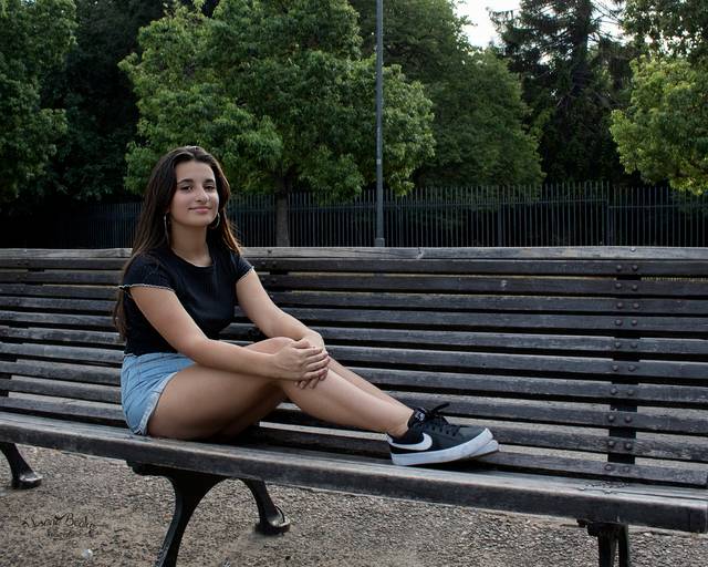 quinceañera sentada en en un banco demadera