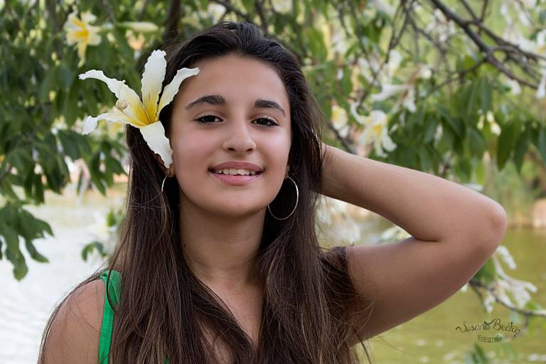 quinceañera tomandose el pelo y flor en la cabeza