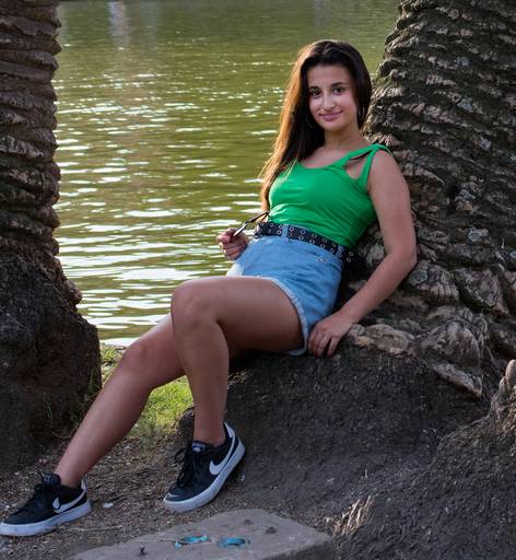 quinceañera recostada sobre el tronco de una palmera