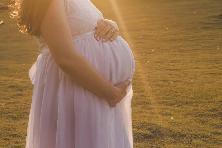 gestante acariciando a barriga na luz do por do sol no Anila Restaurante