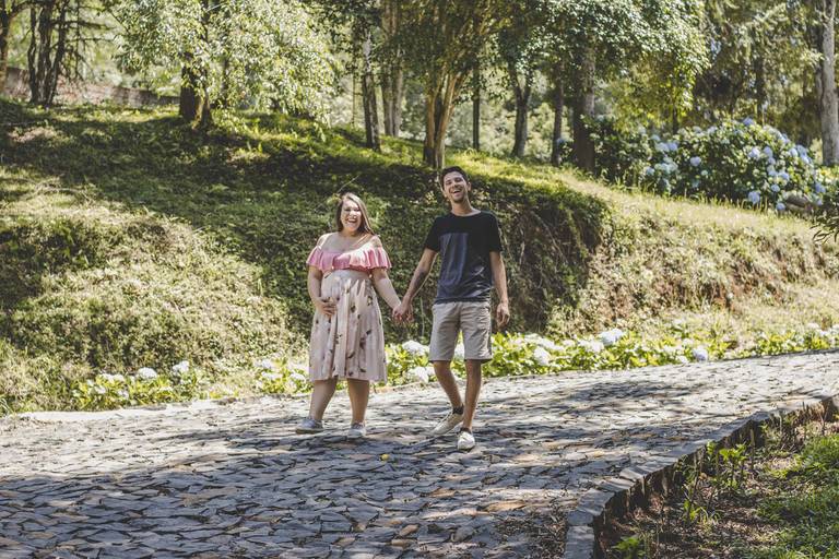 papais jovem felizes caminhando em área verde na sessão gestante