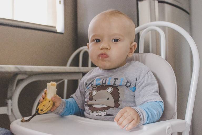 bebe comendo banana na cozinha de sua casa durante ensaio em irati pr