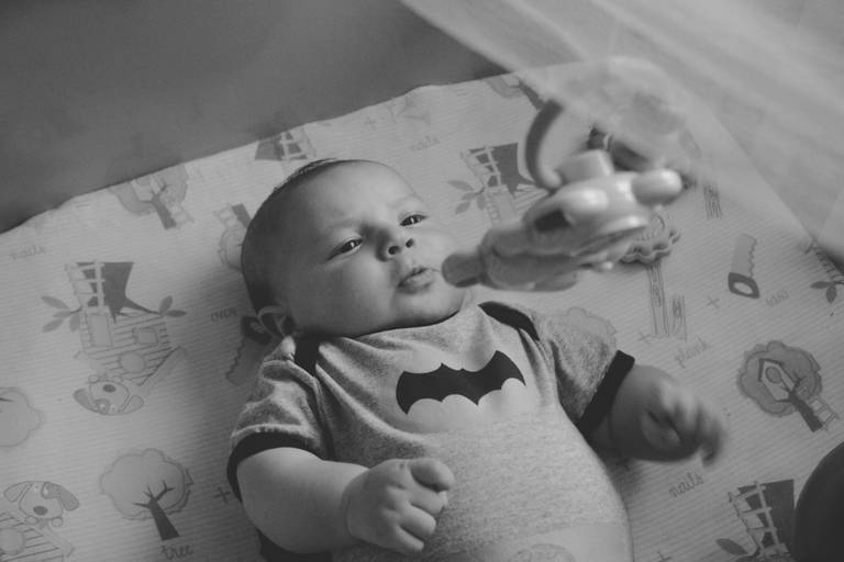 bebe  brincando com mobile de berço vestido de batman