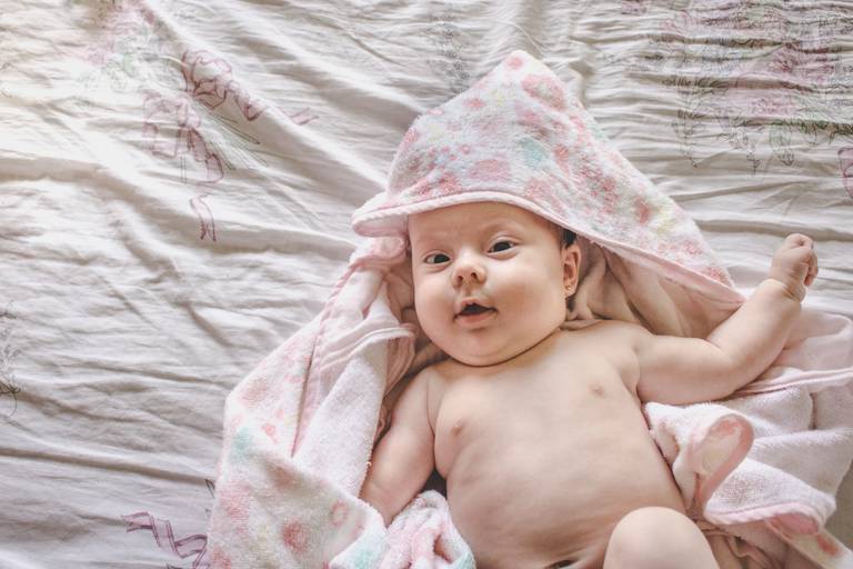 bebe fofo na cama com toalha de banho 