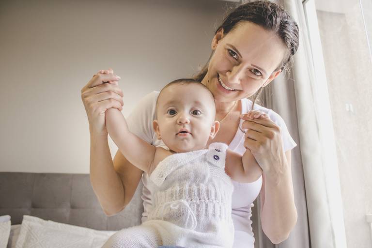 foto de mãe e bebe  vestindo macacão de trico ao lado da janela