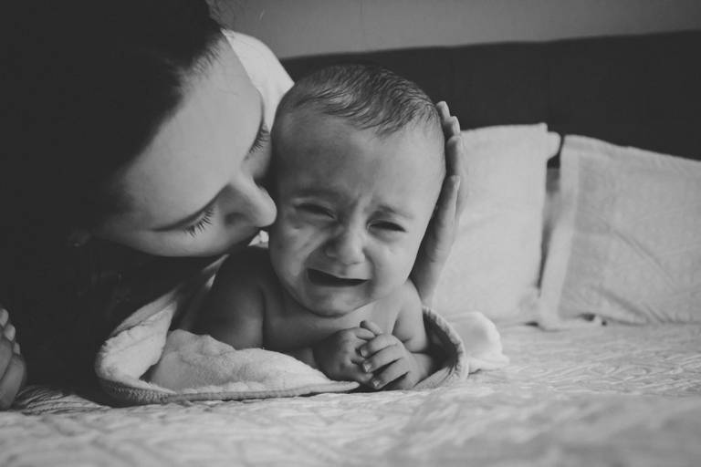 mãe acalmando bebe chorando 