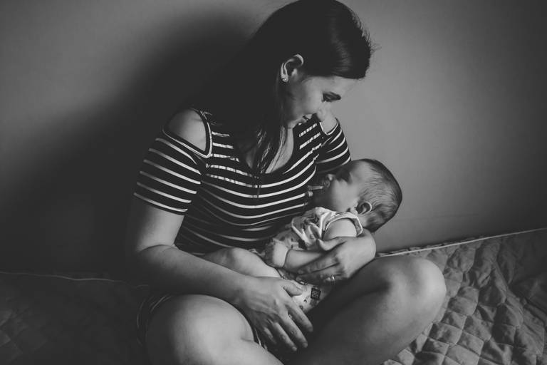 mãe admirando bebe no seu colo durante sono