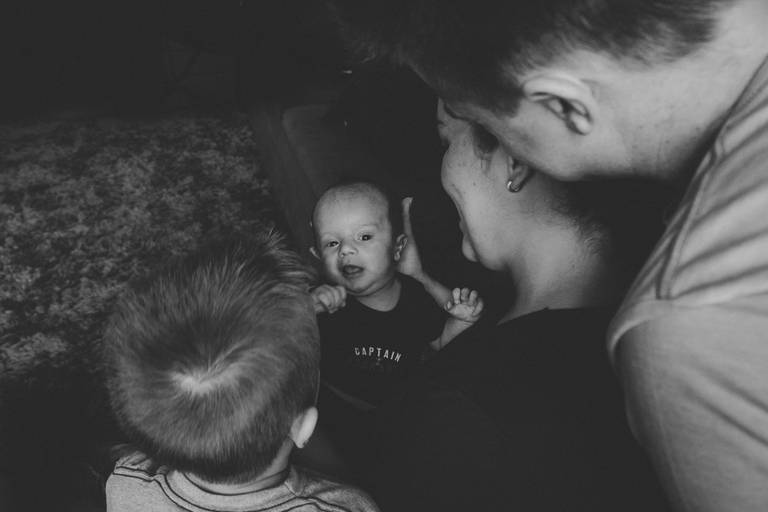 foto em preto e branco de família reunida com recém nascido no colo