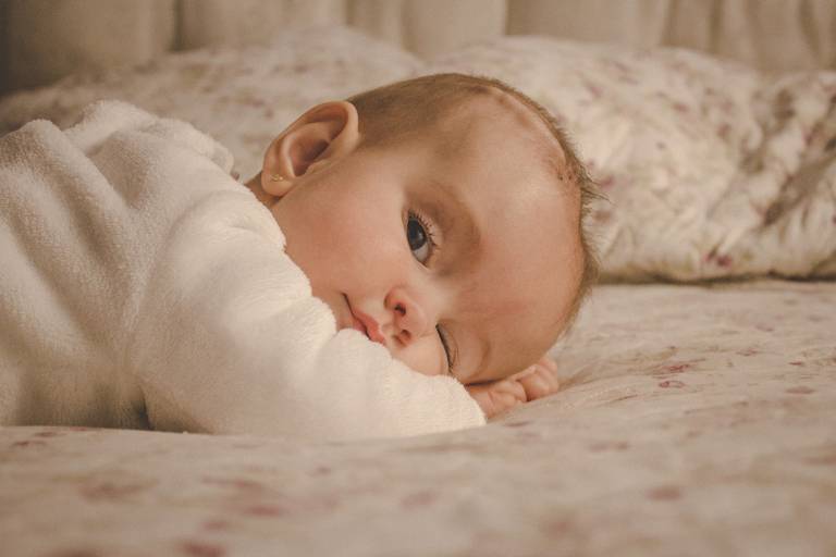 bebe fazendo charme sobre a cama da mamãe