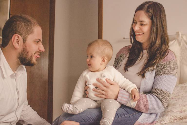 papai fazendo careta pra bebe no colo da mamãe durante sessão de fotos
