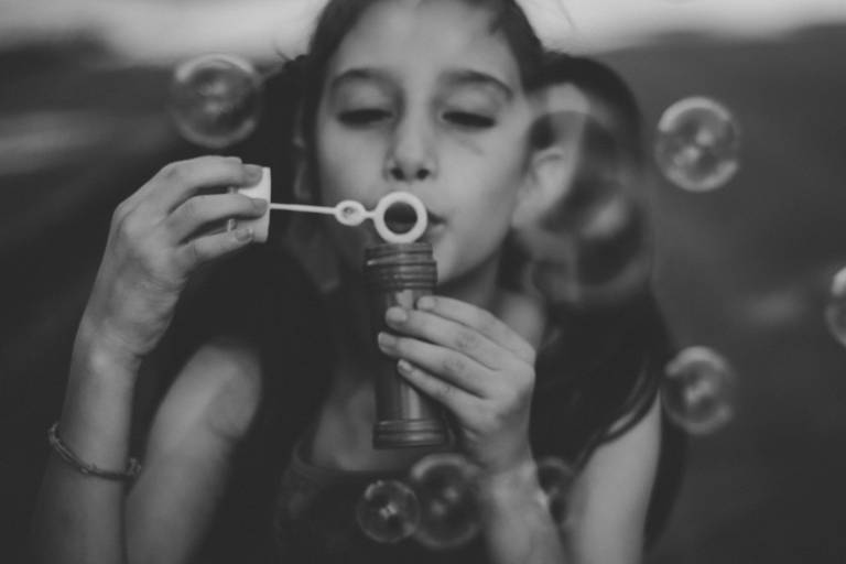 foto de criança brincando com bolha de sabão em preto e branco