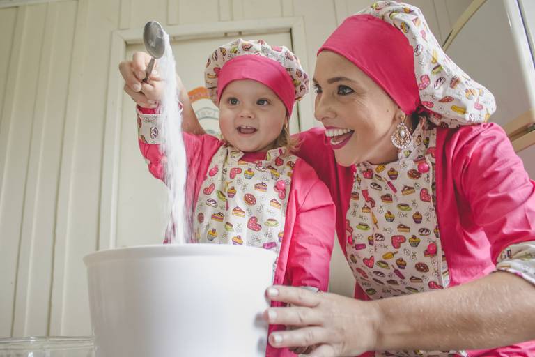 criança e mãe confeiteira fazendo bolo juntas