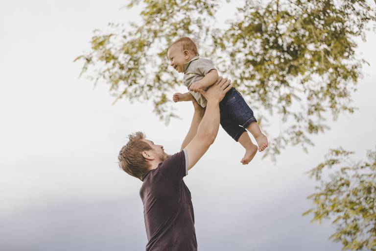 pai jogando bebe pro alto foto com céu nublado