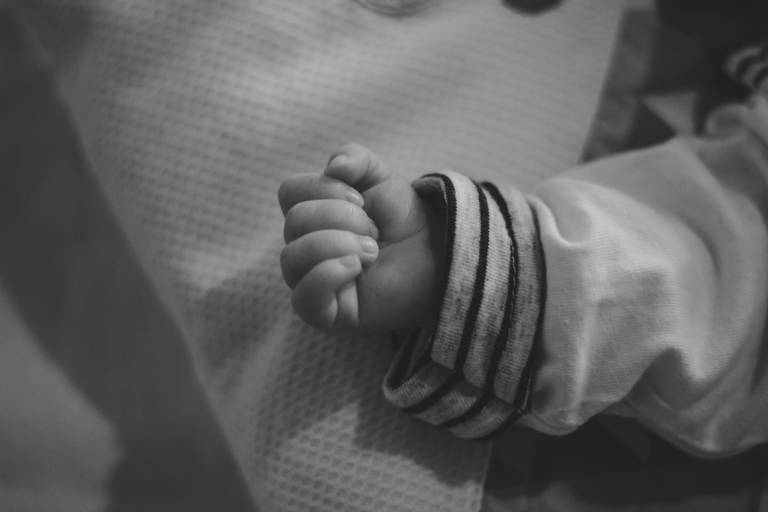 foto em preto e branca com detalhe da mãozinha do recém nascido