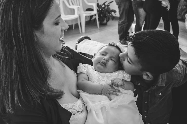 irmão beijando a bebe no dia do seu batismo em irati pr
