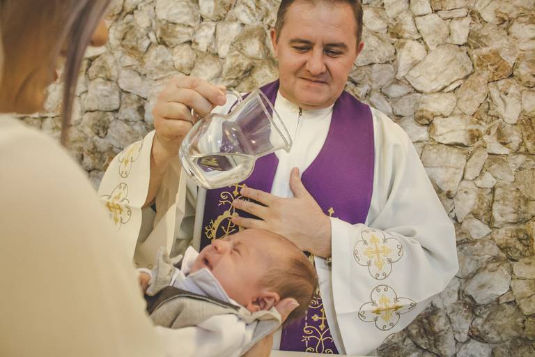 padre derramando a água benta em batismo