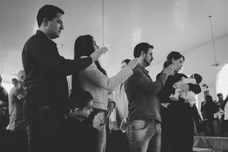 padrinhos e pais abençoando bebe no batizado