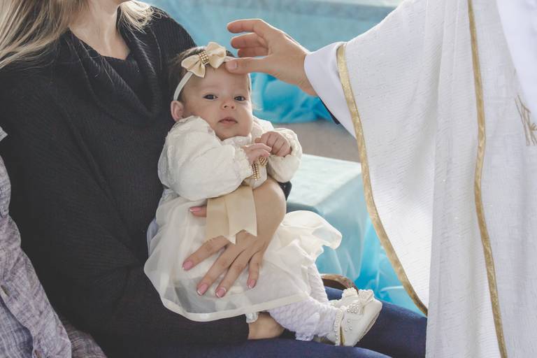 Padre fazendo sinal da cruz na bebe no seu batismo em Irati Pr
