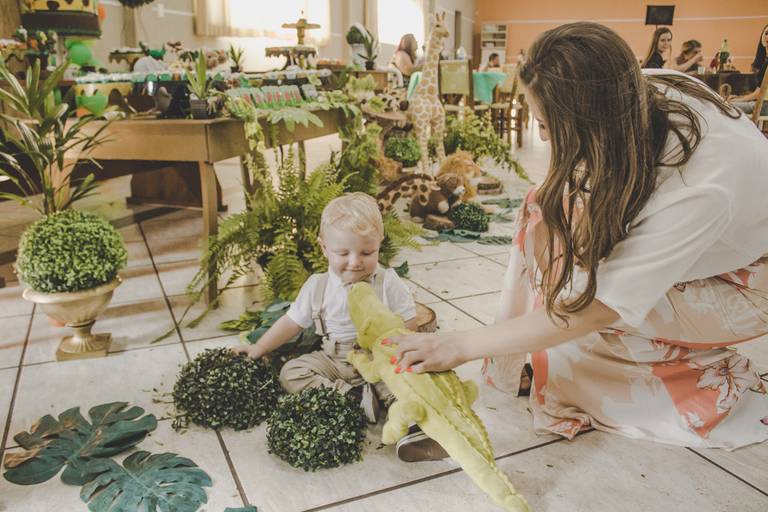 criança brincando com jacaré de pelúcia em aniversário de safári