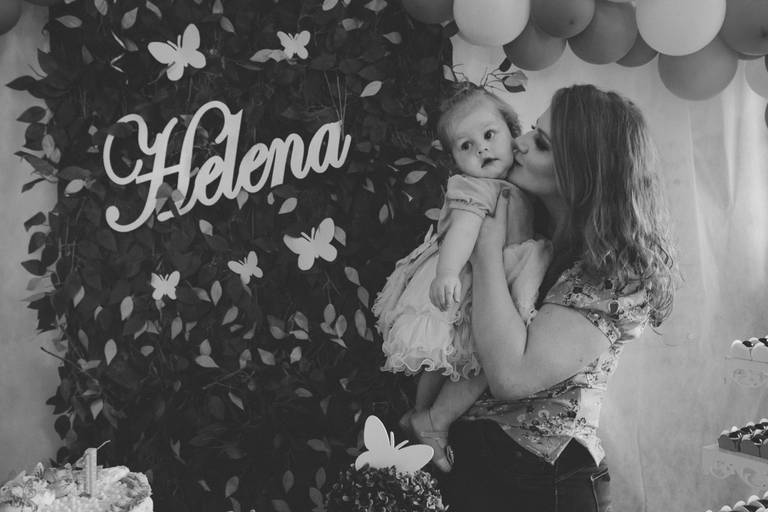 mão beijando bebe em painel de aniversário com tema de jardim...