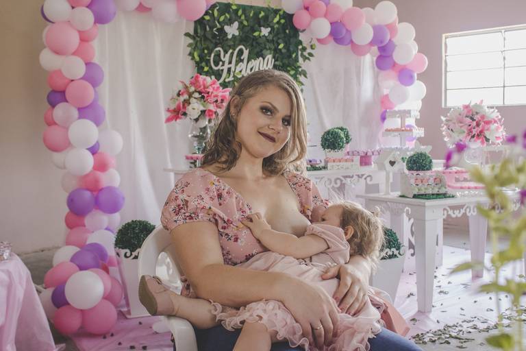 Mãe amamentando bebe com peito de fora em aniversário com tema de jardim