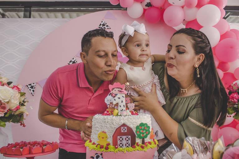 pais assoprando vela na hora do parabéns em aniversário com tema de fazendinha