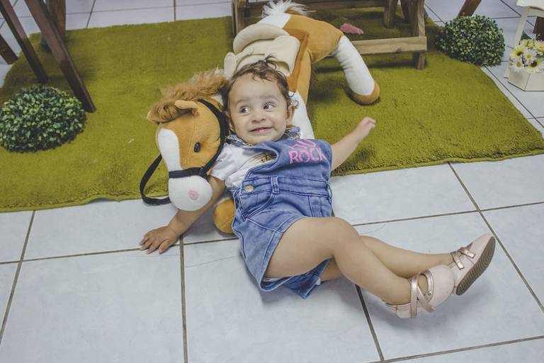 criança fazendo pose com seu cavalinho de pelúcia 